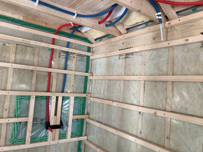 Isolerade väggar med dold rördragning och träreglar i en byggkonstruktion under renovering.