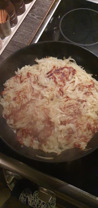 Stekt råraka (potatispannkaka) på en teflonstekpanna över en induktionshäll.