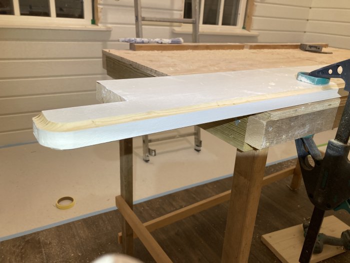 Nyproducerad fönsterbänk av stavlimad furu under målning i snickeriverkstad.