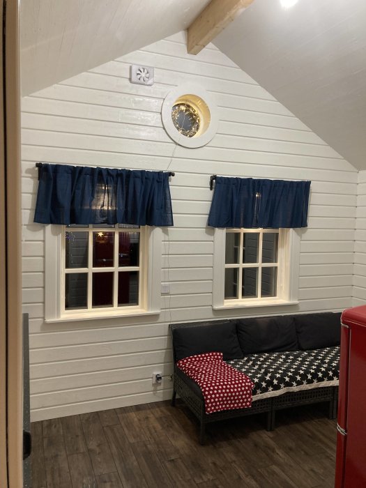 Renoverat rum med trädekor klinkersgolv, vitmålade väggar, blå gardiner och en sittbänk med stjärnmönstrad dyna.