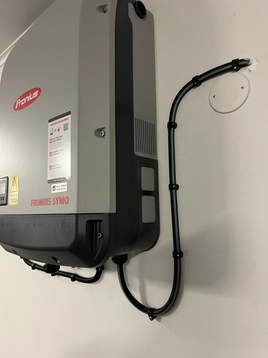 En Fronius Symo solväxelriktare installerad på en vägg med snyggt dragna kablar och utan synlig brandmansbrytare.