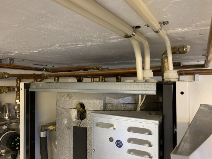 Utrymme under golvet med värmesystemets rör, kopplingar och en del av en värmemodul.