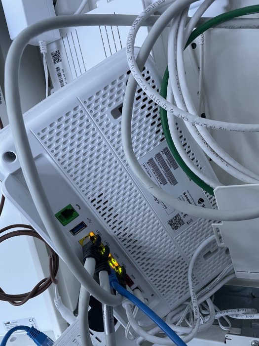 Nätverksrouter med anslutna Ethernet-kablar och aktivitetslampor som lyser.