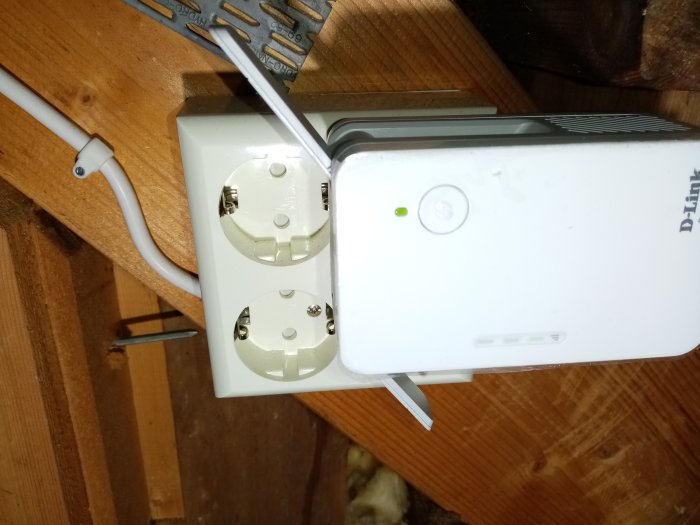 En RJ45 nätverkskabel ansluten till en D-Link AC1300 Wi-Fi Range Extender monterad på vägg.