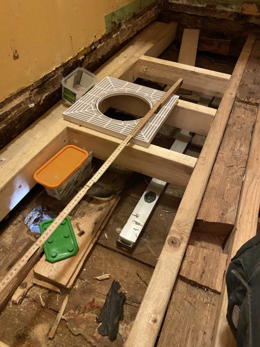 Renovering av golv med reglar, vattenpass fastklämt under träklossar i en tvättstuga.