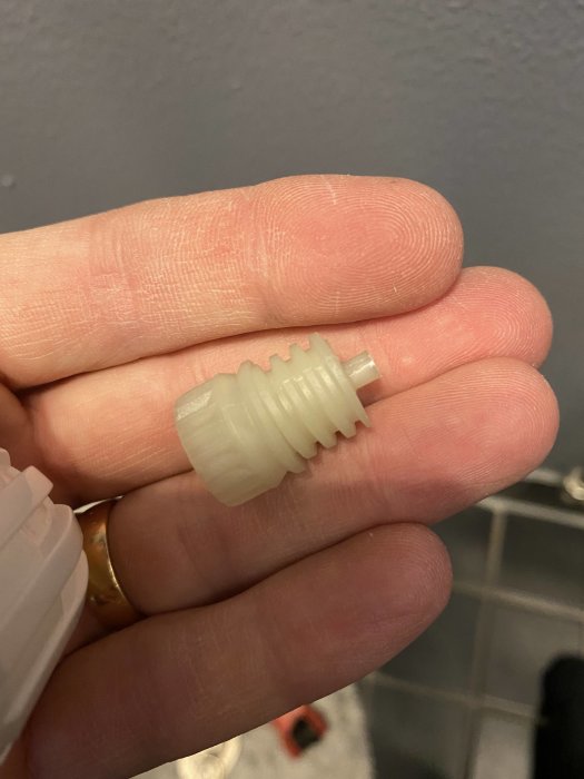 Vit plastkägla för termostat hållen mellan fingrar som visar möjlig bristande längd.