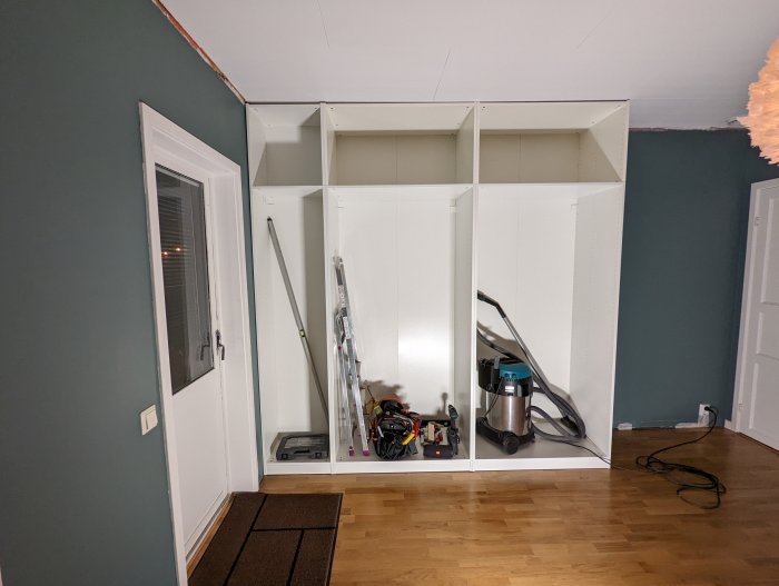 Överskåp installerade ovanför garderob i ett rum med verktyg och städutrustning.