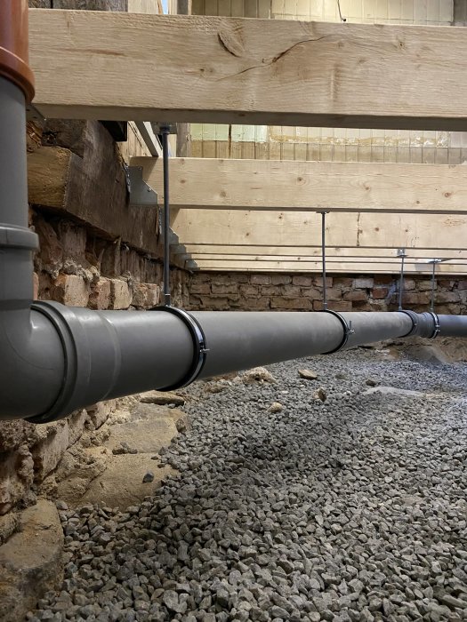 Nya rörinstallationer i grusfyllt utrymme under renovering, troligen för framtida badrum.