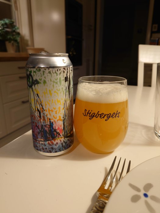 Ölburk med graffiti-design bredvid ett glas fyllt med öl, märkt "Stigbergets".