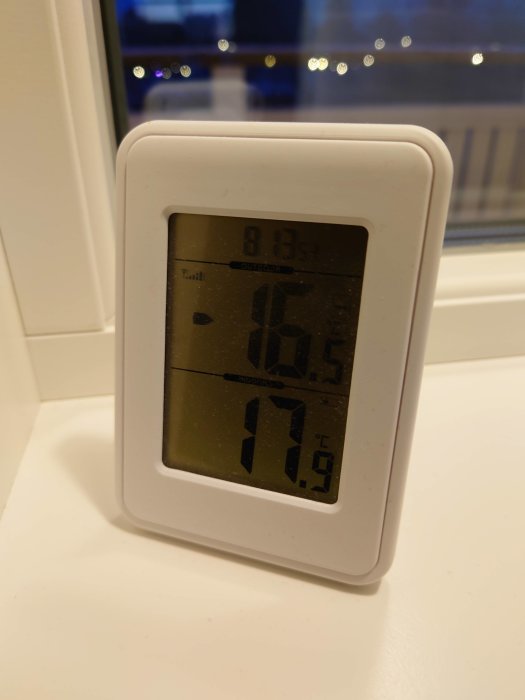 Digital termometer visar inomhus- och utomhustemperatur på fönsterbräda.