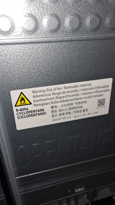 Ny samsung kylskinnsida med fettliknande substans vid en varningsdekal om brandfarligt material.