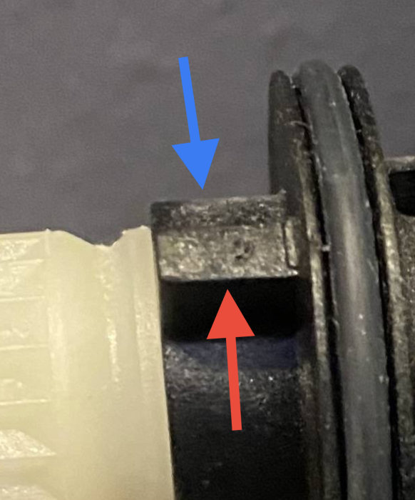 Detaljbild på termostatventil med markerat minläge med blå pil och maxläge med röd pil.