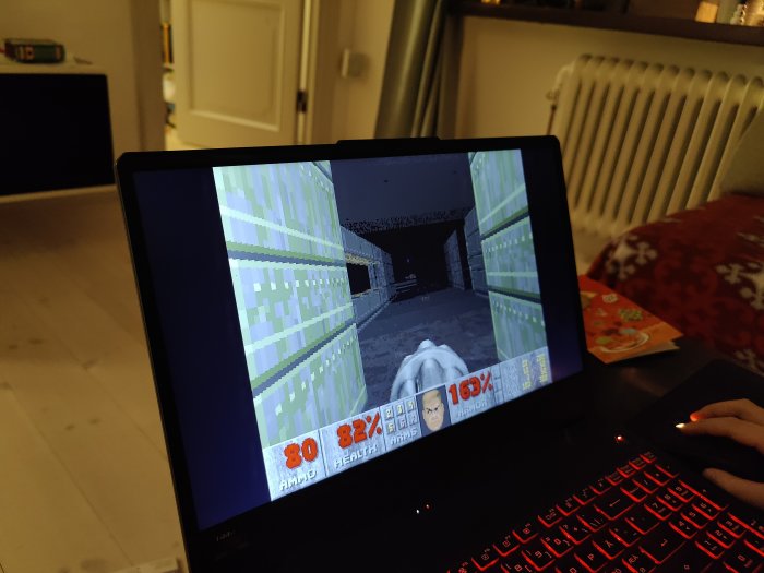 Laptop med klassiskt Doom-spel på skärmen, återspeglar sonens reaktion på grafiken.