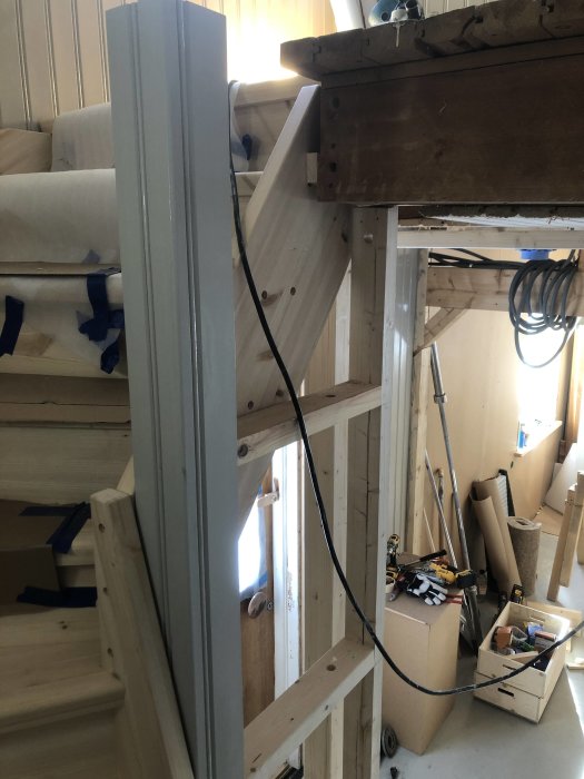 Obyggd trätrappa i ett trapphus med konstruktionsmaterial och verktyg synliga runt omkring.