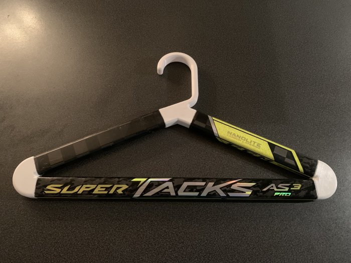 En ishockeyklubba märkt "SUPER TACKS AS3 PRO" med svart tejpad handtag och en vit bladspets på mörk bakgrund.