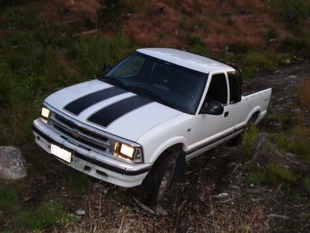 Vit pickup med höjd fjädring och bodylift parkerad i terrängen.