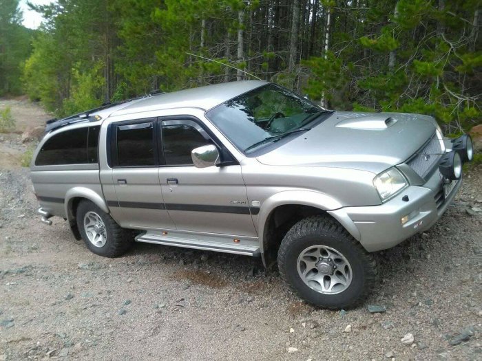 Silverfärgad pickup med 4-tums höjning parkerad i skogsmiljö.