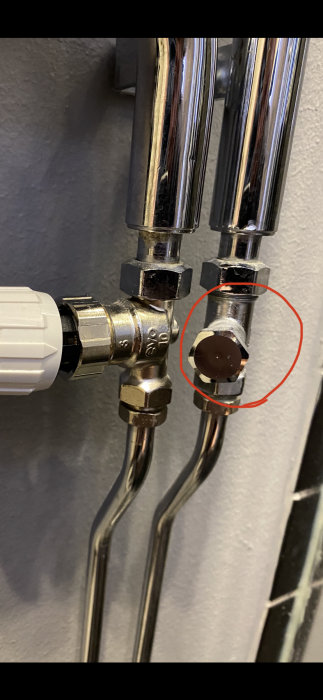VVS-installation med rör och termostat, markering runt ett lock som inte ska lossas utan försiktighet för att undvika vattenläckage.