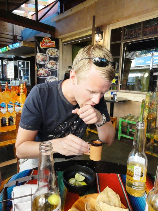 Person äter nachos och dricker öl på en restaurang i Tijuana, ser misstänksam ut på salsakoppen.