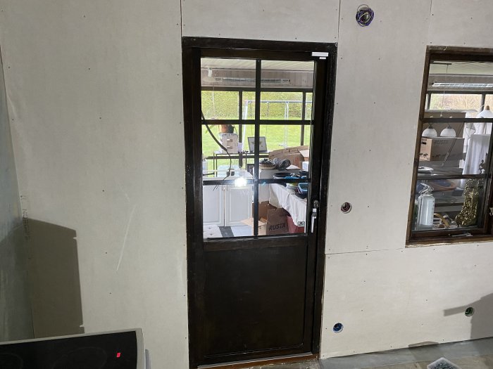 Renoveringsrum med nyinstallerade gipsskivor på väggar och synlig balk strax ovanför en dörr.