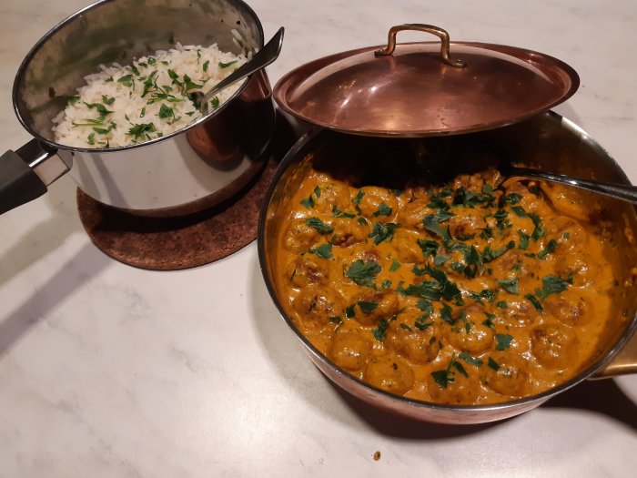Köttbullar i mandelsås med hackad persilja, serverade med ris i en kastrull.