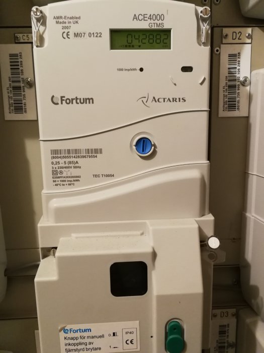 Elmätarskåp med en Fortum ACE4000 mätare, inställningsknappar och varningsetiketter.