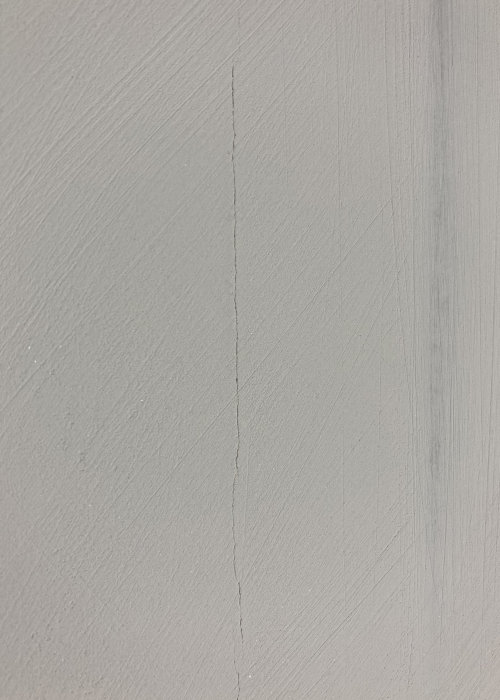 Spricka i gråmålad renoveringsgipsvägg längs skarven mellan gipsskivor.