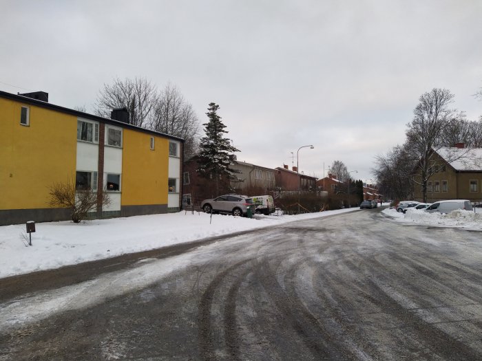 Gata i vinterväder med snötäckta trottoarer och en gul byggnad, där stolpar tycks ha flyttat sig.