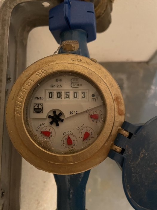 En vattenmätare visar en avläsning på 503 kubikmeter med röda och svarta mätarskivor i fokus.