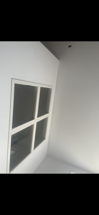 Vägg med spricka ovanför fönster indikerande potentiella strukturella skador i ett hus.