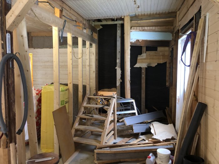 Trapphus under renovering med isoleringsmaterial, träreglar och byggbråte.