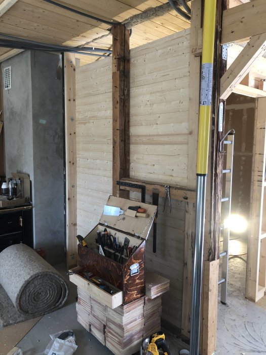 Renovering av hus med nya träväggar och takbjälkar, verktygslåda och byggmaterial synligt.