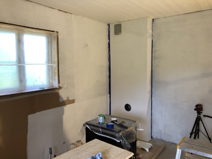 Renoverat hörn av ett rum under konstruktion med isolering, oavslutade väggar och synlig eldragning.