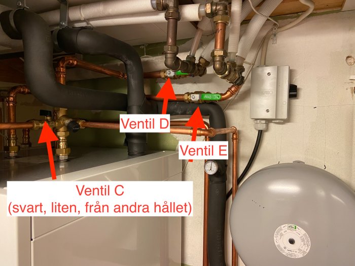 Bergvärmepumpinstallation med märkta ventiler och rörledningar för underhåll.