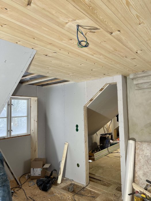 Innertak under konstruktion med 22mm furuplank och nedhängd kabel, vid en delvis byggd vägg.