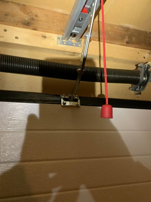 Garageport med synlig fjäder och fästet för automatisk öppning som kan behöva förstärkning.