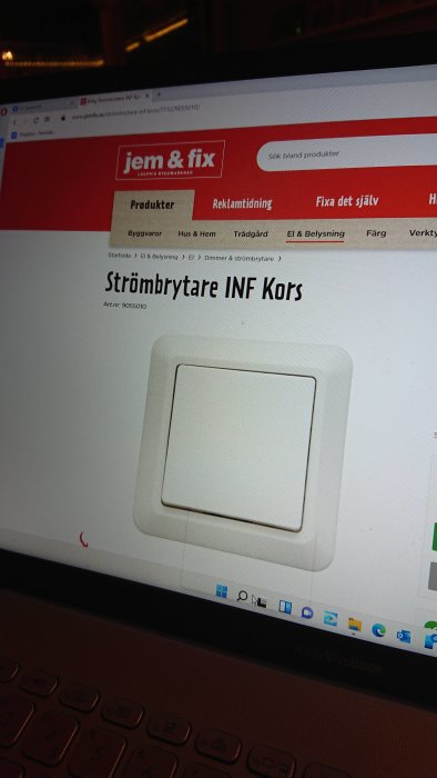 Vit strömbrytare av modellen "INF Kors" på en webbutiks produktsida visad på en laptop-skärm.