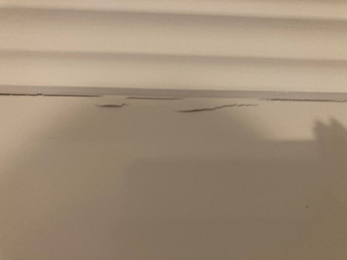 Sprickor längs med taklister och vägg som visar möjliga skador efter husets rörelser.
