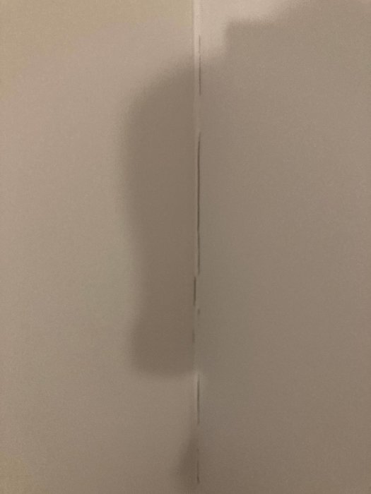 Spricka längs med skarven mellan två spånskivor på en vägg i ett rum, tecken på rörelse i byggnaden.