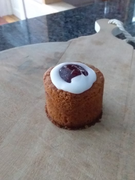 En kaka med vit glasyr och röd sylt på en köksbänk.