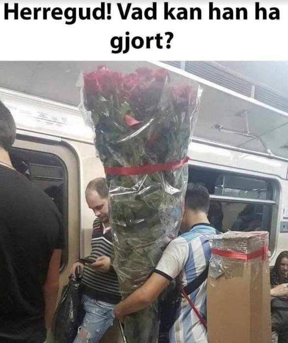 Man i tunnelbana döljd bakom en stor bukett rosor, med omkringstående passagerare.