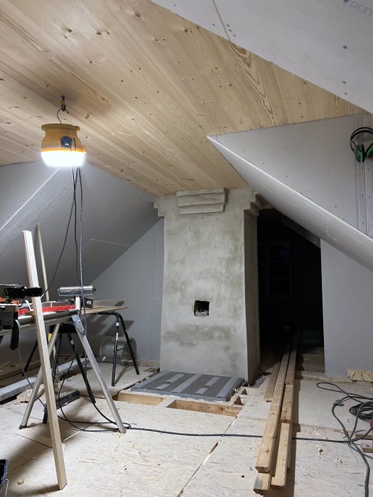Renoverat övervåningstak med träpaneler och taklister på golvet i en byggarbetsmiljö.