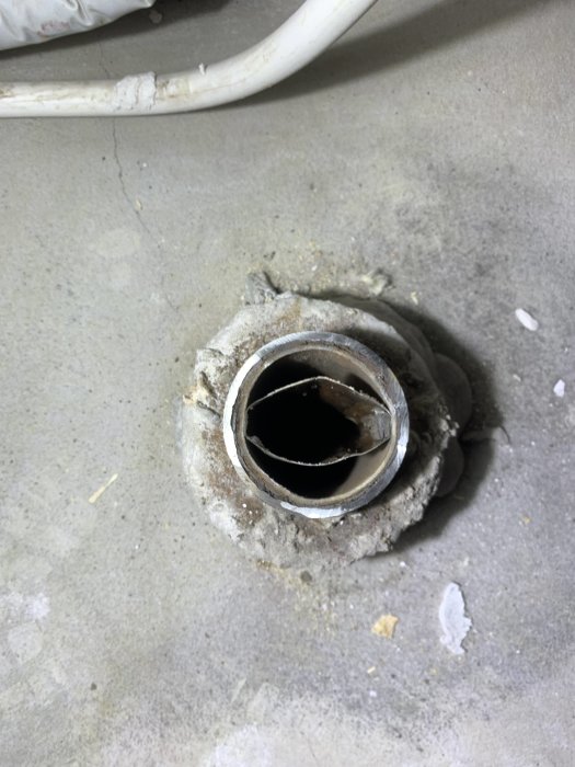 Relinat avloppsrör med synlig pappstrumpa inne i ett större rör, inlagt i betonggolv.