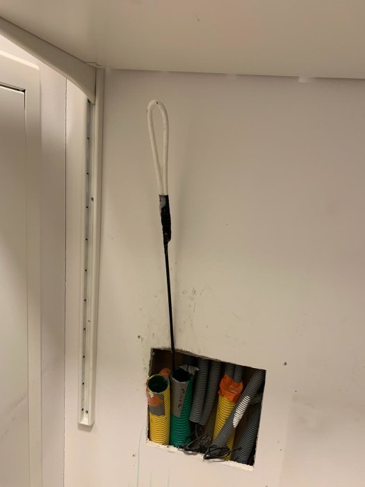 En rörål sticker upp från ett golvgenomföring med flera färgade installationsrör.