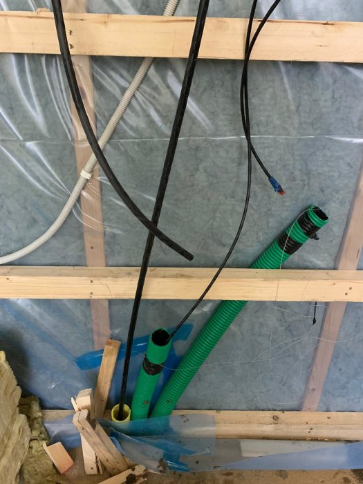 El- och nätverkskablar dragna genom en rörål i en väggkonstruktion under renovering.