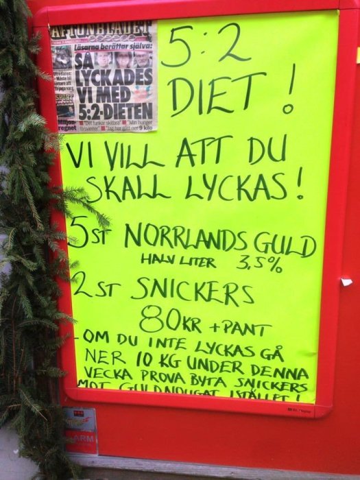 En skylt med texten "5:2 DIET! VI VILL ATT DU SKALL LYCKAS!" och erbjudanden på Norrlands Guld och Snickers.