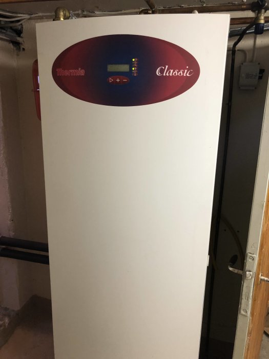 Värmepumpens framsida med en digital display visande status och varumärket Thermia Classic.
