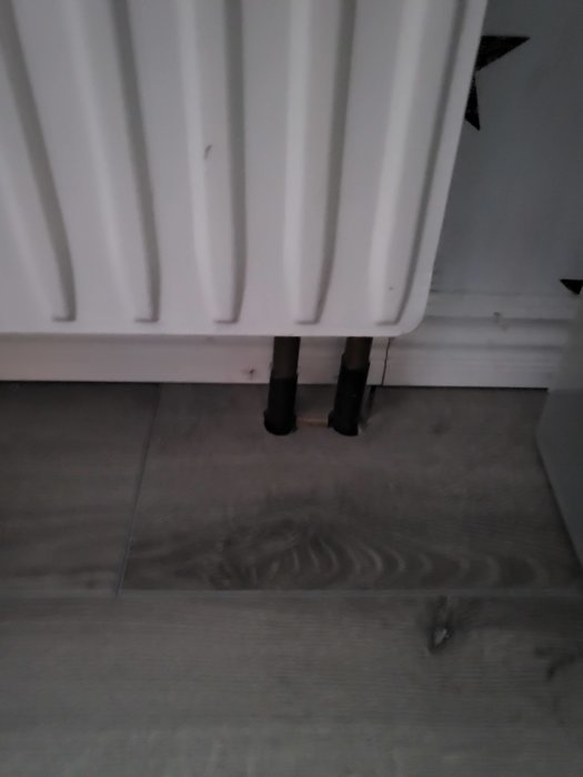 Vattenburna element med synliga rör mot golv, inför borttagning för fönsterinstallation.