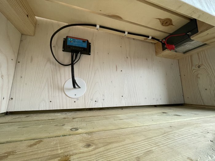 Installation av batteri och belysningskontroll under en bänk i ett omklädningsrum.