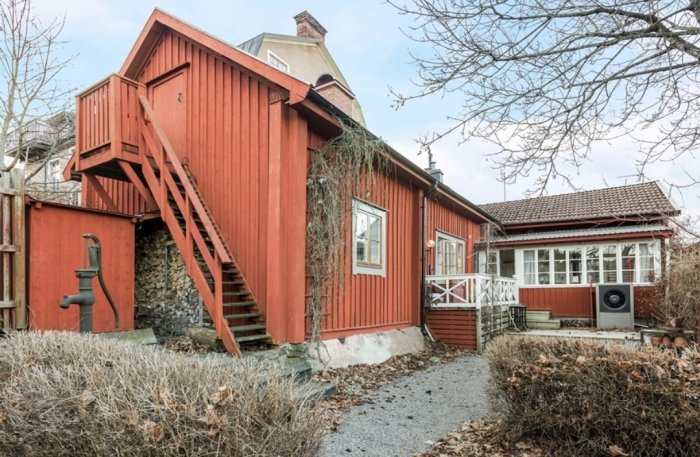 Rött trähus med vita knutar och utomhustrappa, traditionell svensk arkitektur.